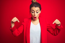 Young Beautiful Business Woman Standing Over Red Isolated Background Pointing Down With Fingers Showing Advertisement, Surprised Face And Open Mouth