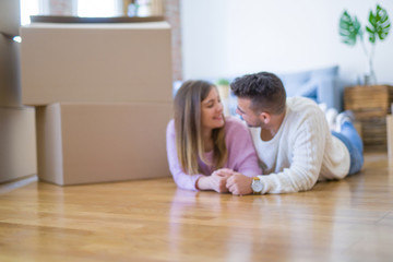 Wall Mural - Young beautiful couple in love moving to new home, lying on the floor around cardboard boxes, very happy and cheerful for new apartment