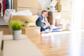 Wall Mural - Young beautiful couple relaxing sitting on the floor around cardboard boxes at home, smiling happy moving to a new house