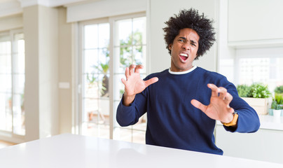 Sticker - Young african american man wearing casual sweater sitting at home afraid and terrified with fear expression stop gesture with hands, shouting in shock. Panic concept.