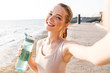 © Drobot Dean - Sports woman outdoors on beach take a selfie by camera.