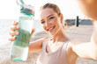 © Drobot Dean - Sports woman outdoors on beach take a selfie by camera.
