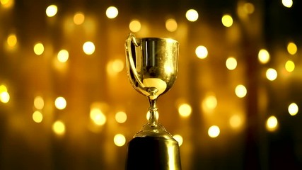 gold trophy turn around competition in the dark on the abstract blurred light background with copy s