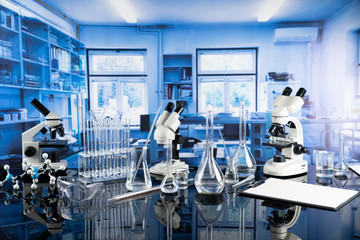 Modern scientific laboratory interior. Laboratory glassware and microscope on the glass table.