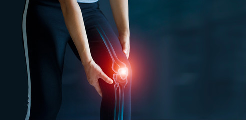 Sport woman suffering from pain in knee. Tendon problems and Joint inflammation on dark background. Healthcare and medical.