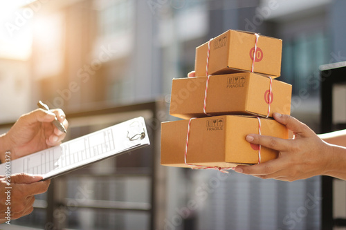 Fotomural Delivery man holding parcel boxes while a man is signing documents in morning ba