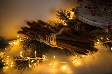 Christmas toys, garlands and interior elements in lights, home decoration for the holiday. Tied cinnamon sticks, kerosene lamp, glowing stars, lights in the side.