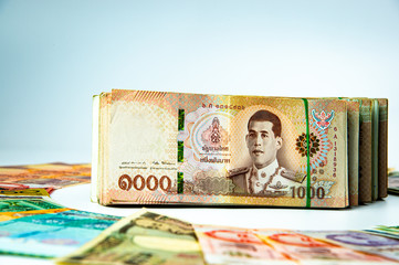 Stacked of Thai money bank note in the middle of international money.