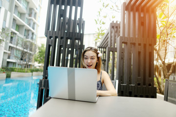 Wall Mural - Cheerful woman rejoice With laptop near swimming pool.