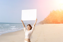 Woman In Bikinis Holding Blank White Board On The Beach.