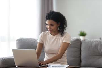 Wall Mural - African American woman busy working on laptop from home