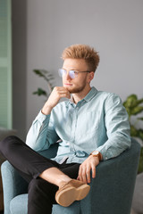 Sticker - Portrait of stylish young man sitting in armchair at home