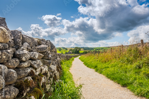 Fotografía Low level view of a very old, stone wall seen extending to an abandoned farmhouse in the distance