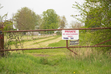 hallow focus of a makeshift Private Property sign seen at the entrance to private pasture. Secured by a metal gate to prevent trespassers during darkness.