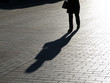 Silhouette and shadow of lonely woman with handbag walking on a street. Concept of dramatic life, vulnerability, loneliness
