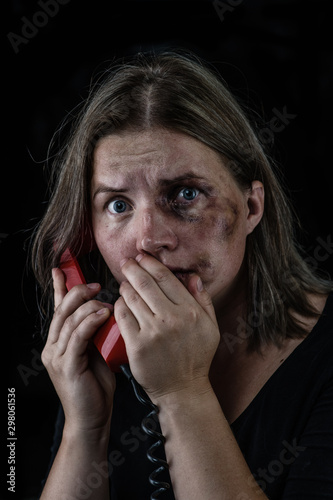Woman victim of domestic violence and abuse asks for help by phone. Empty space for text. Isolated on dark background