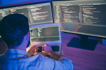 Poster - Rear behind view photo of it skilled specialist guy sitting night comfy office holding hands on keyboard looking many monitors testing team task finishing debugging