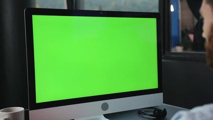 Mock-up chrome key green computer monitor on office table. Close-up manager working by personal computer in modern company.