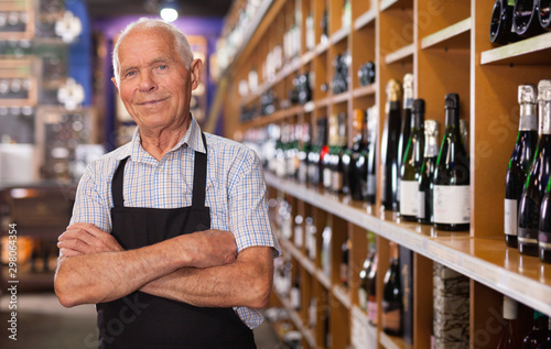 Cuadros en Lienzo Portrait of confident senior vintner posing smiling in wineshop interior