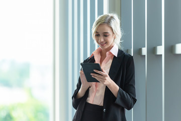 Business women using smart phone or mobile to work and checking information of financial data and connection technology in model office city town.   Business Concept.