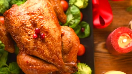 Wall Mural - Christmas Roasted Chicken Dinner. Winter Holiday table served, decorated with candles. Delicious Steamed Roast chicken over wooden background with Christmas gifts, table setting. Dolly shot 4K UHD