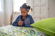 African American girl prays by the side of her bed.