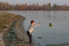 Little Boy Child Throws Plants Into The Water