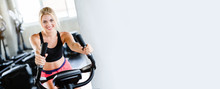 Women Wearing Sportswear Doing Workout Activity, Spinning An Electric Bicycle In The Gym For Good Health Have A Beautiful Shape And Allowing The Muscles To Relax. Copy Space On Banner Background.
