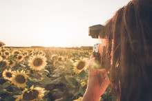 Crop Unrecognizable Photographer Standing In Middle Of Field With Bright Sunflowers And Taking Picture Of Sunset