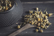 © Jose Luis Alvarez/ADDICTIVE STOCK - Closeup of dried daisy heap in wooden spoon on dark table for tea making