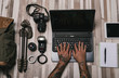 © Jordi Calvera/ADDICTIVE STOCK - Overhead crop man with tattooed hands typing on laptop keyboard near photography equipment and stationery on lumber surface