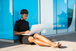 © Rafa Cortes/ADDICTIVE STOCK - Side view of concentrated African American woman in elegant black dress using laptop while relaxing on pavement on street