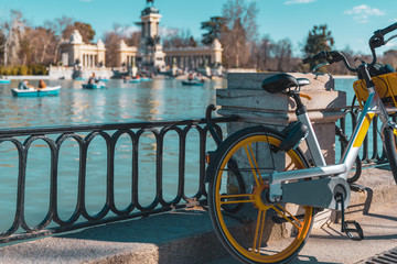 Electric bicycle rental in the foreground and the park of the Retiro in the background out of focus. Sustainable lifestyle