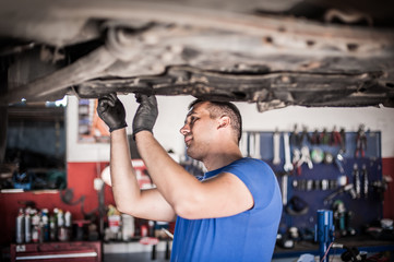 Wall Mural - Auto mechanic repairer checking condition under car on vehicle lift