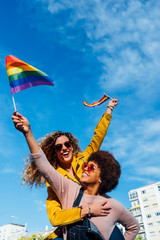 Two women friends hanging out in the city waving LGBT in Madrid city