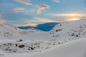 Wall Mural - snow mobile with metal trailer parked on the rocky side of a small snow covered mountain in the arct