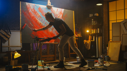 Fototapete - Talented Male Artist Working on a Abstract Painting, Uses Industrial Roller To Create Daringly Emotional Modern Picture. Dark Creative Studio Large Canvas Stands on Easel Illuminated