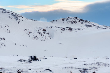 Wall Mural - snow mobile with simple trailer parked in snow covered mountains with no people and (barely) visible