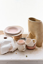 Different Baked Products From Clay. Ceramic Mugs, Vases And Plates Are On The Windowsill