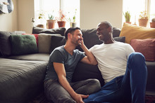 Two Homosexual Men Smiling And Sitting On Floor