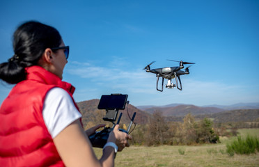 A woman is piloting a drone driving it from a remote control.