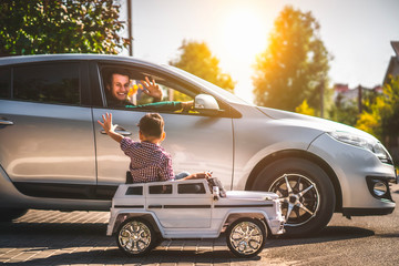 the father and his little son driving their cars