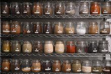 Close Up Of Spices In Air Tight Jars Arranged On Shelves