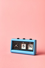 Old Flip Clock And Calendar On A Pastel Background, Color Of The Year 2019 Living Coral Pantone. Date 5, Day THU, Thursday.