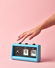 Woman's Hand Turns Off The Button On Retro Flip Clock With Calendar Day Thuesday, Date 5, On A Background Color Of The Year 2019 Living Coral .