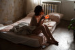 © Dmytro Bilous/Stocksy - girl without clothes sits on the bed and lights a cigarette