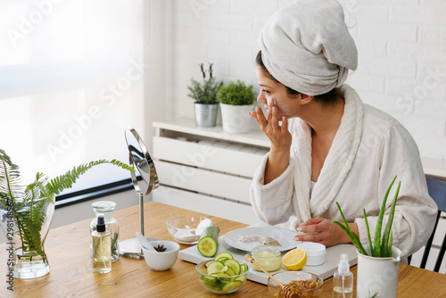 Fotomural Young woman applying face mask at home