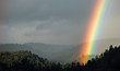 © Carolyn Lagattuta/Stocksy - Bright rainbow shining on a valley of trees