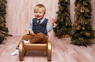 Wall Mural - a boy near the Christmas trees on a sled, Christmas lights, rejoices and smiles, plays. holiday and vacation