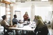 © Maskot - Businesswoman discussing business plan with colleagues in meeting at board room
